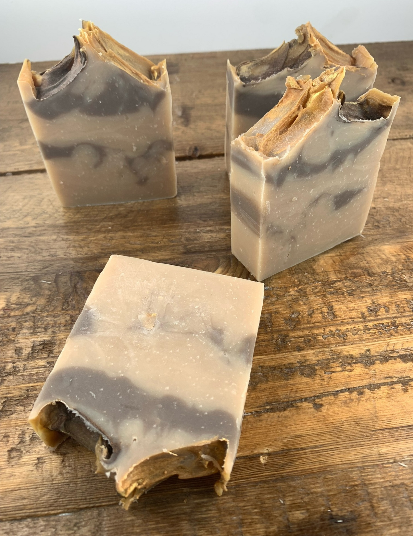 A brown swirled soap with a golden top sits on a wooden table. This cashmere scented soap is delightful with a warm and soft scent.