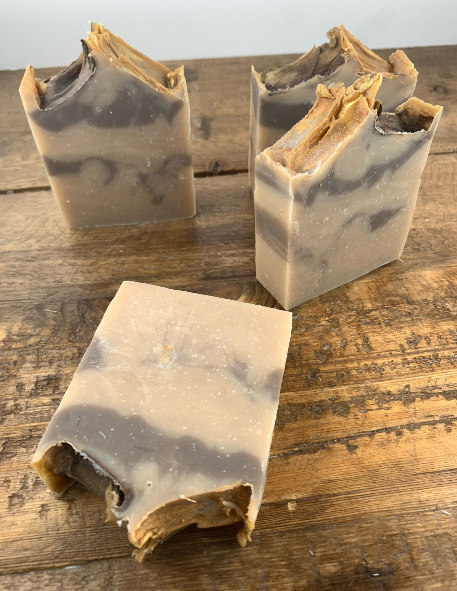 A brown swirled soap with a golden top sits on a wooden table. This cashmere scented soap is delightful with a warm and soft scent.