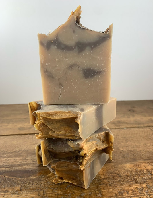 A brown swirled soap with a golden top sits stacked on more bars of the same soap on top of a wooden table. This cashmere scented soap is delightful with a warm and soft scent.