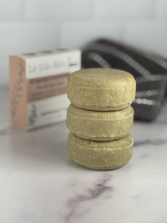 Stack of Le Silo Bleu Strengthening solid shampoo bars on a marble surface with a blurred background