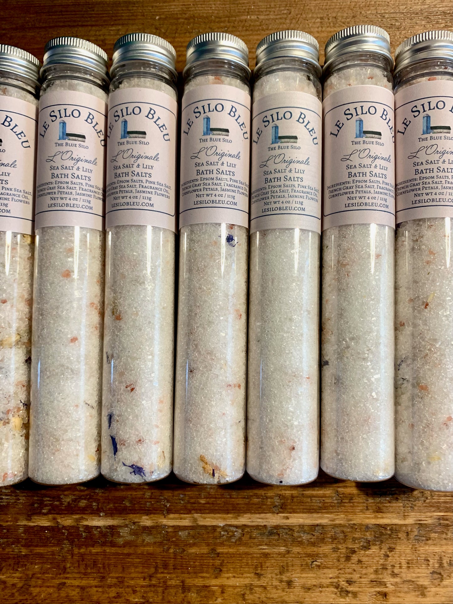 Several tubes of bath salts sit on top of a wooden table.