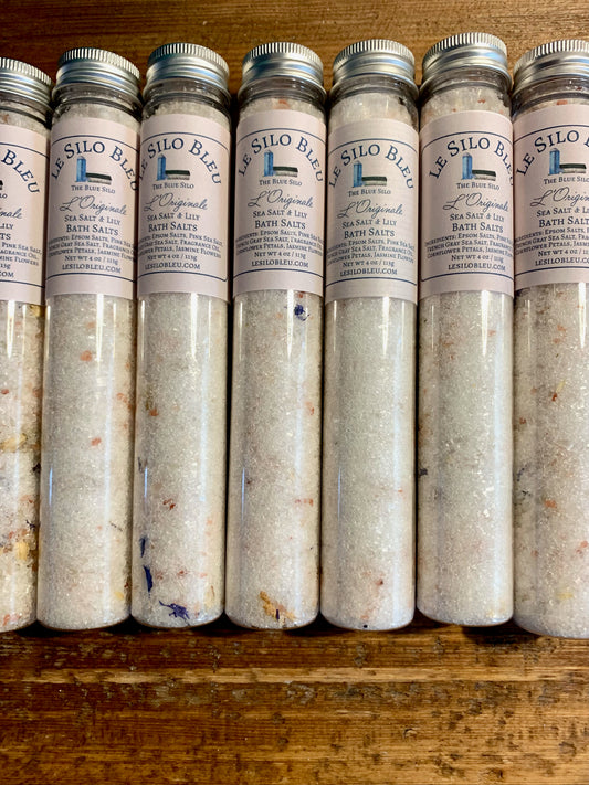 Several tubes of bath salts sit on top of a wooden table. 
