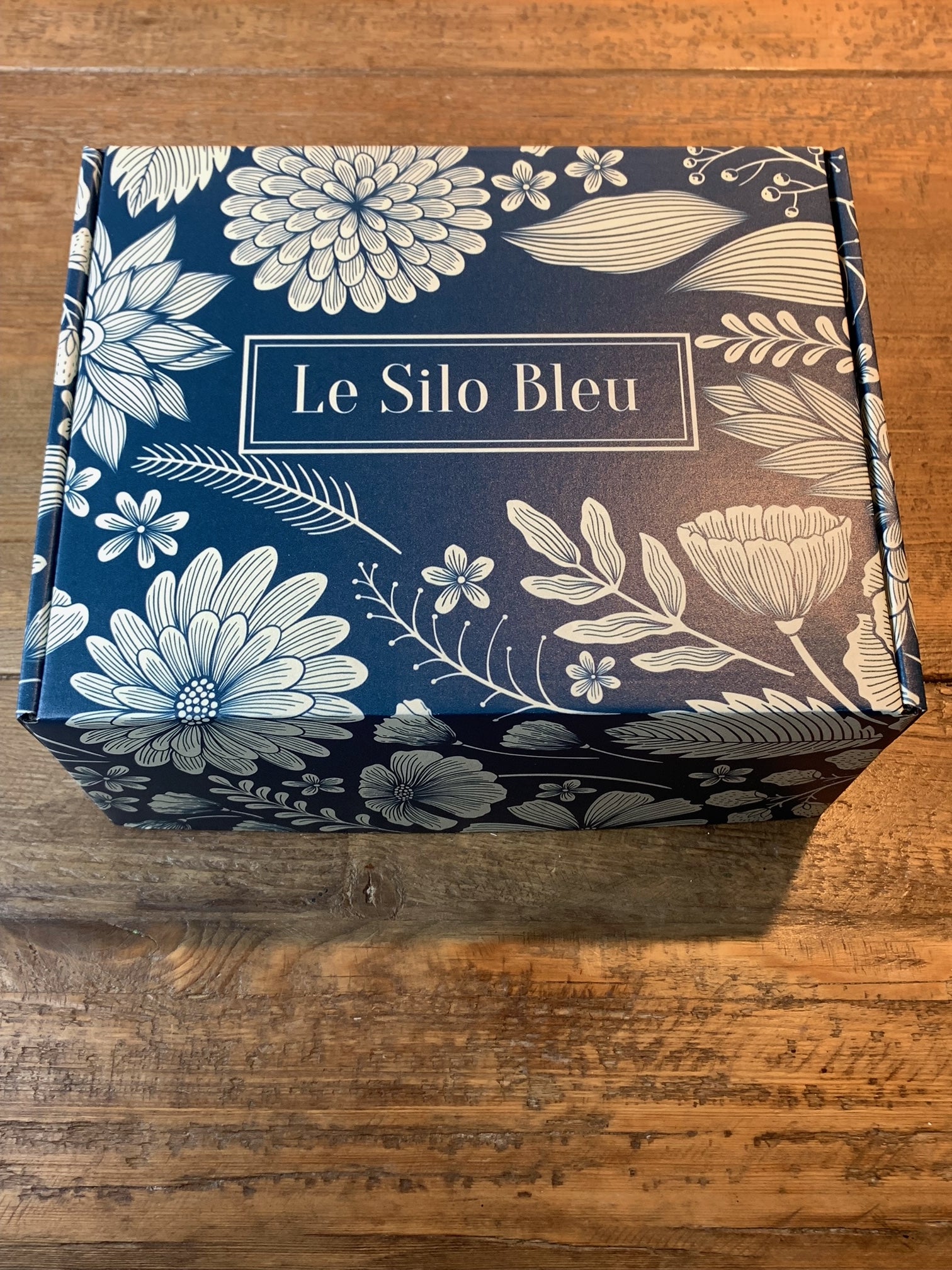 Le Silo Bleu branded premium gift box. Blue with white flowers and leaves imprinted on the box. 