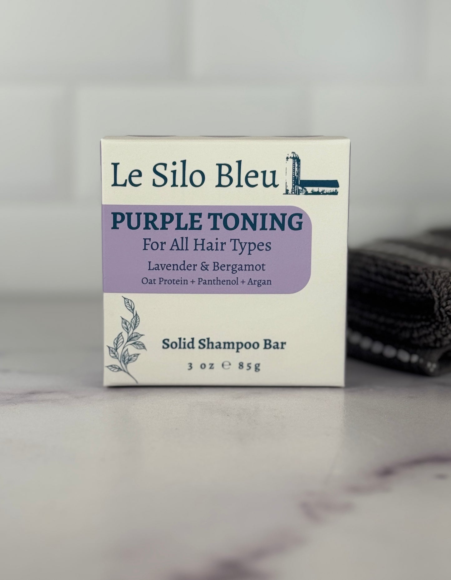 Le Silo Bleu purple toning solid shampoo bar packaging on a marble surface.