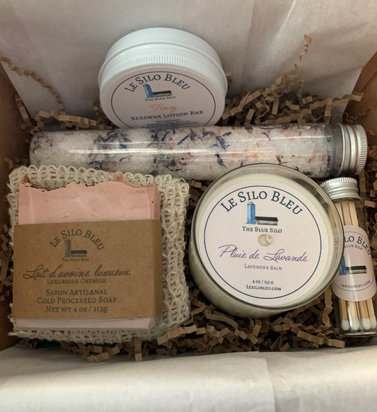 Pamper Yourself Gift Box - Includes Lotion Bar, One Bar Cold Processed Soap with Soap Saver Exfoliating Bag, Small 4 ounce candle, Bath Salts and Matches.  This box is open and shows the contents nestled in natural brown crinkle paper with white tissue paper that will be folded over it once it's packed in the natural box with natural ribbons and tied in a bow. 