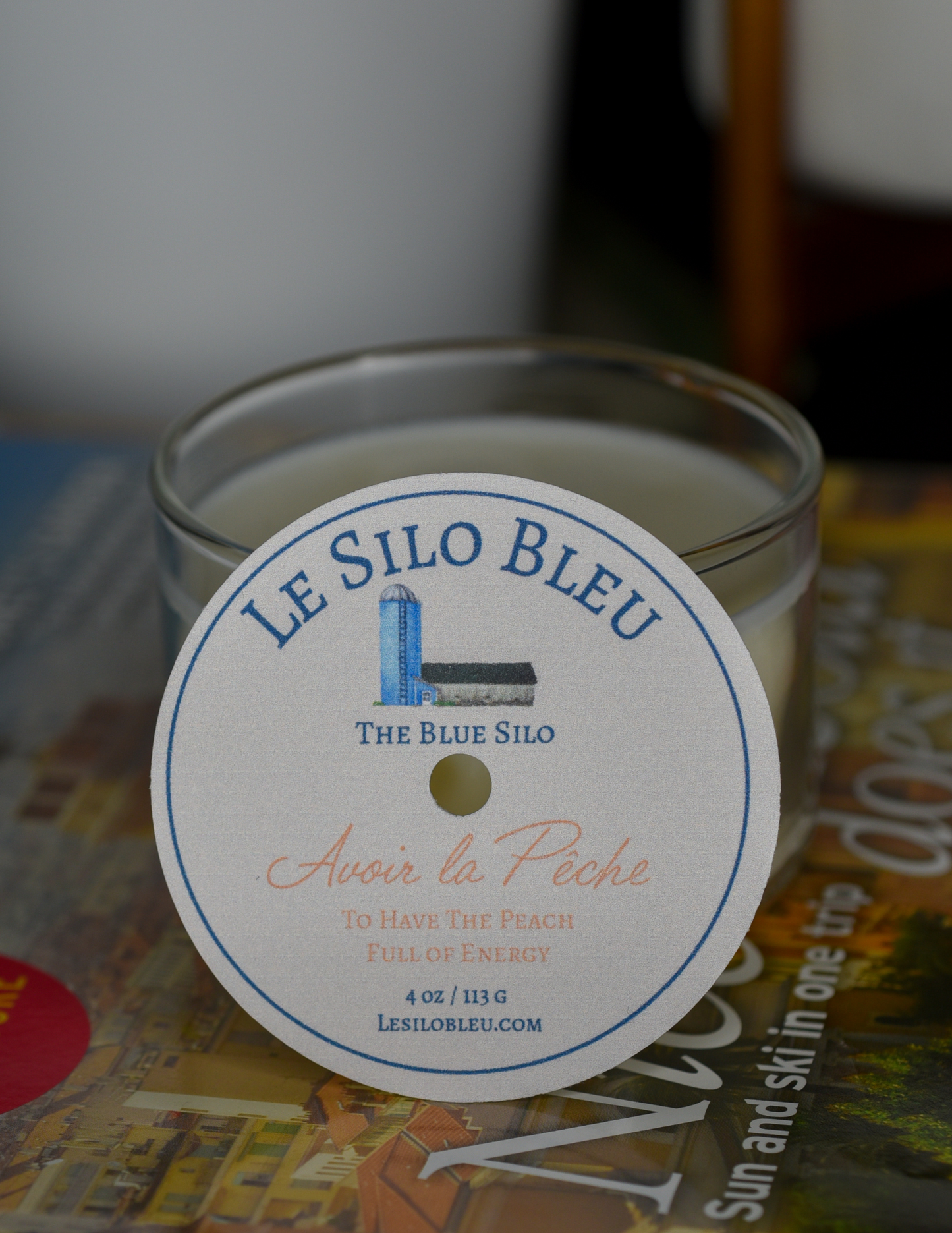 Peach scented candle Candle is sitting on top of a French magazine with a plant in a white jar in the background.