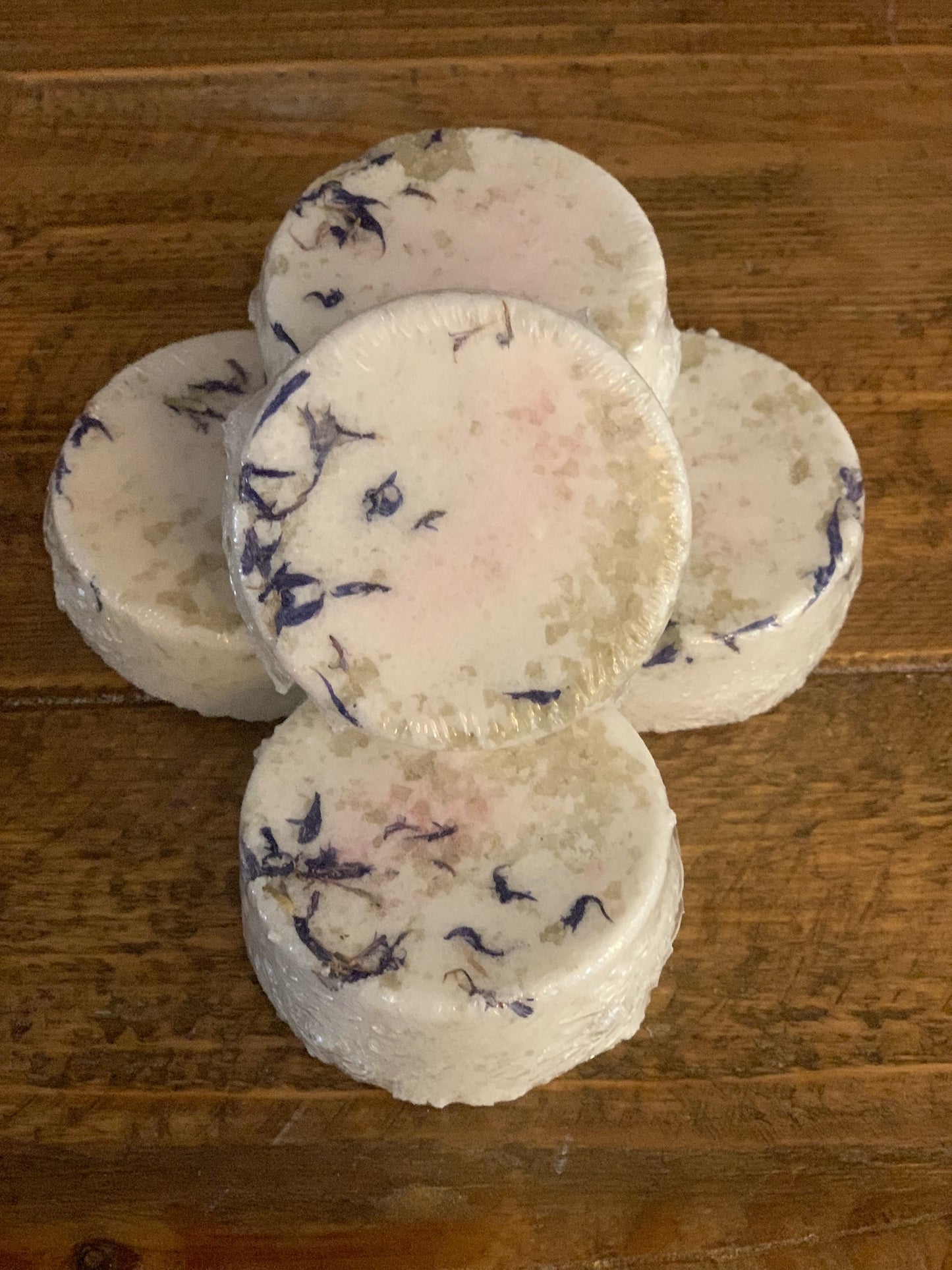 French Gray Sea Salt Bath Bombs stacked and leaning on a wooden table top. 
