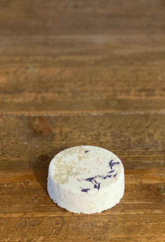 French Gray Sea Salt Bath Bomb with Blue Cornflowers sitting on a wooden table top.