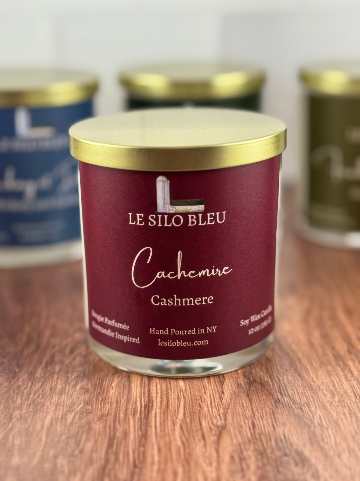 Cashmere scented soy wax candle with 'Le Silo Bleu' label on a wooden surface with other candle jars in the background