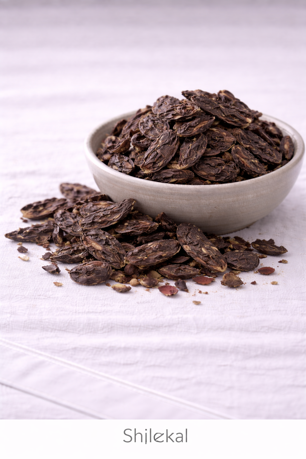 Dried Shikakai in a bowl on a linen tablecloth with other pods around the bowl.