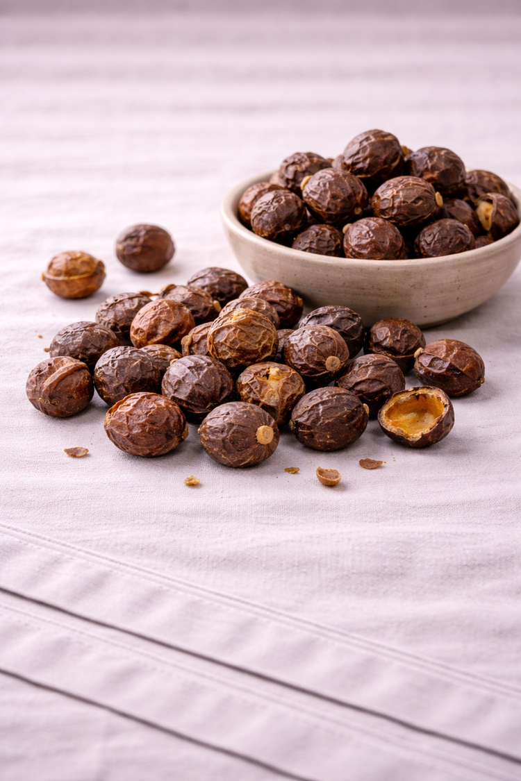 Aritha aka Soapnuts sitting in a rustic bowl with additional nuts around it on top of a linen tablecloth