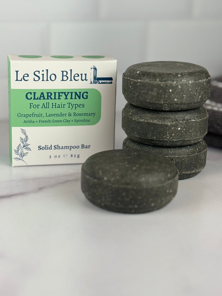 A stack of three and a single Clarifying shampoo bar sitting on a marble table with a white tile backsplash in the background.