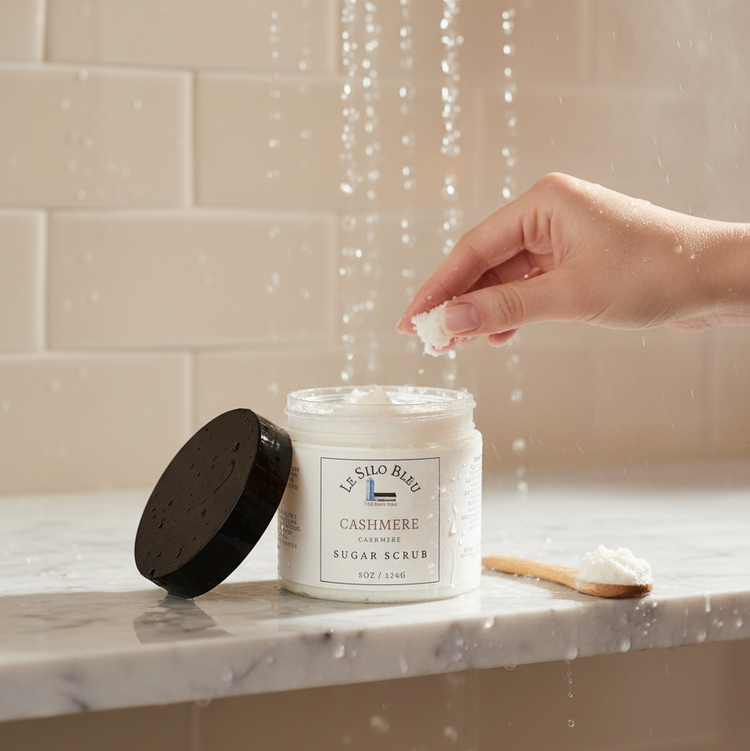 Hand taking a pinch of sugar scrub  from in the shower stream of water. Shower scene with tiled surface and an open jar of sugar scrub