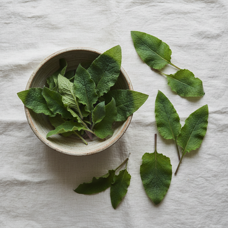 Comfrey leaves in a rustic bowl sitting on a linen tablecloth.