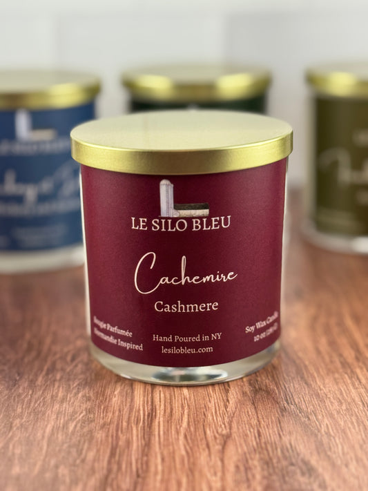 Cashmere scented soy wax candle with 'Le Silo Bleu' label on a wooden surface with other candle jars in the background