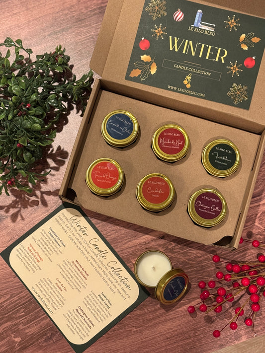 Set of six candles in a 'Winter' collection box with decorative elements on a wooden surface.