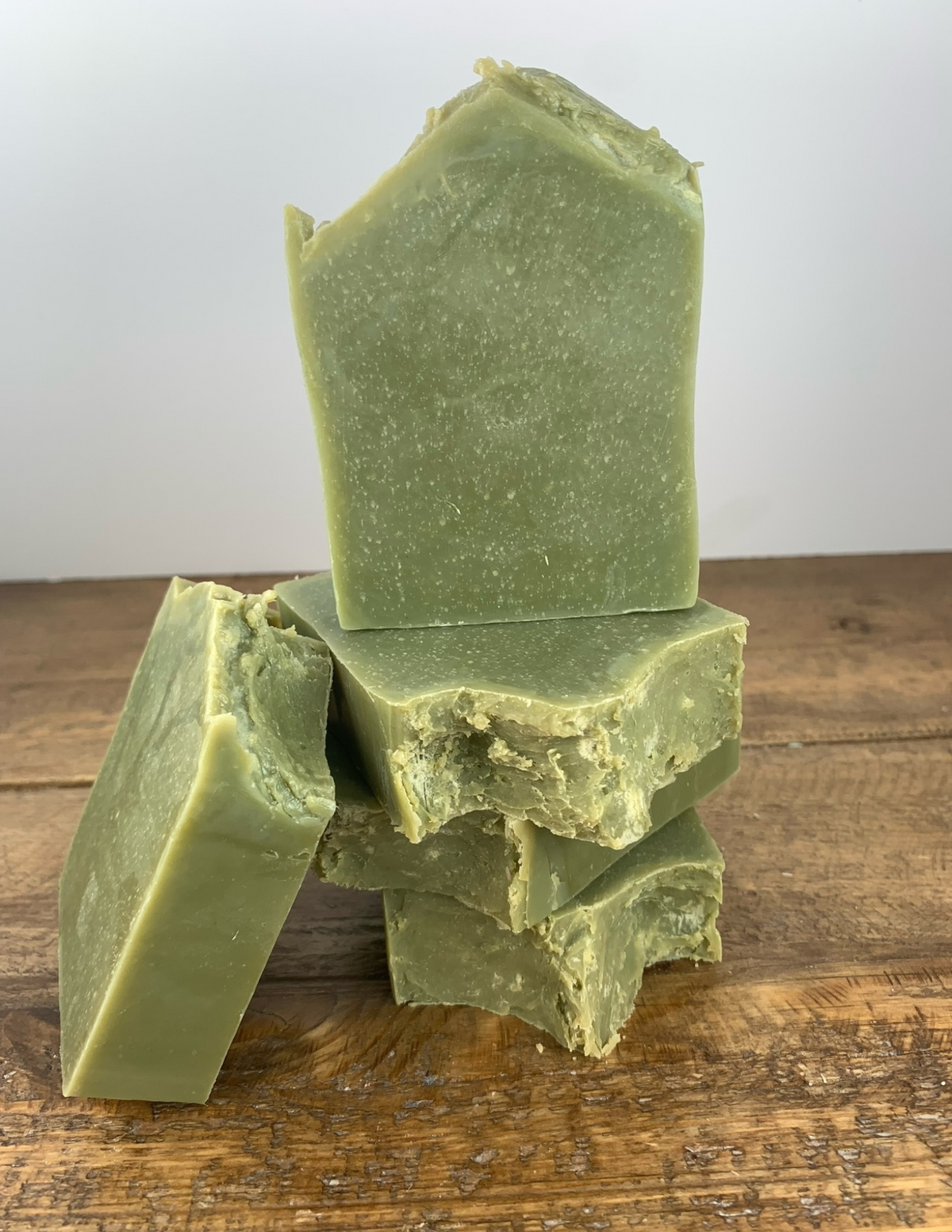 Bars of handmade aloe and spearmint soap colored with spurlina sitting on a wooden tabletop. 