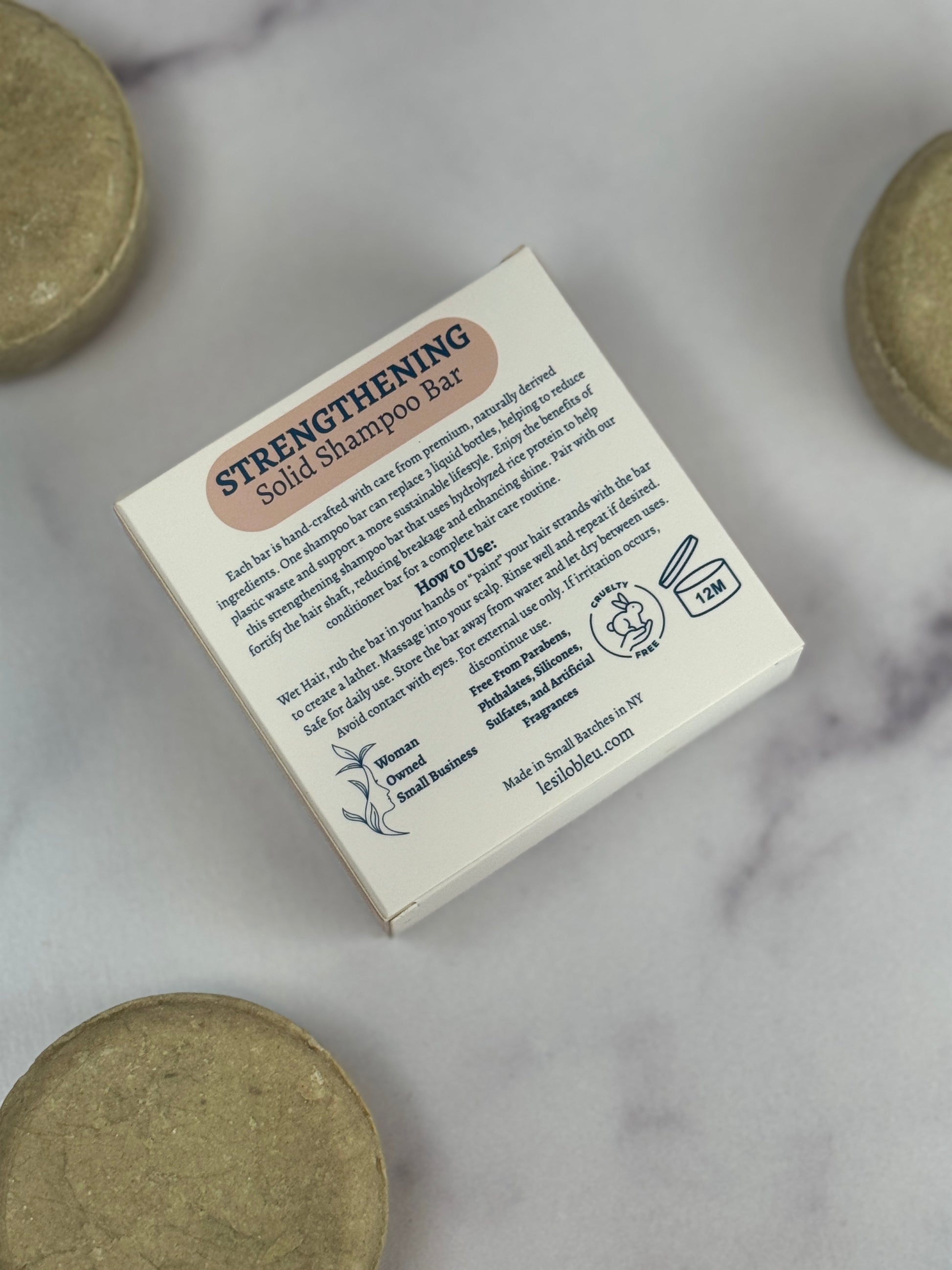 Back of the Box of Strengthening Solid Shampoo Bar with shampoo bars on a marble background