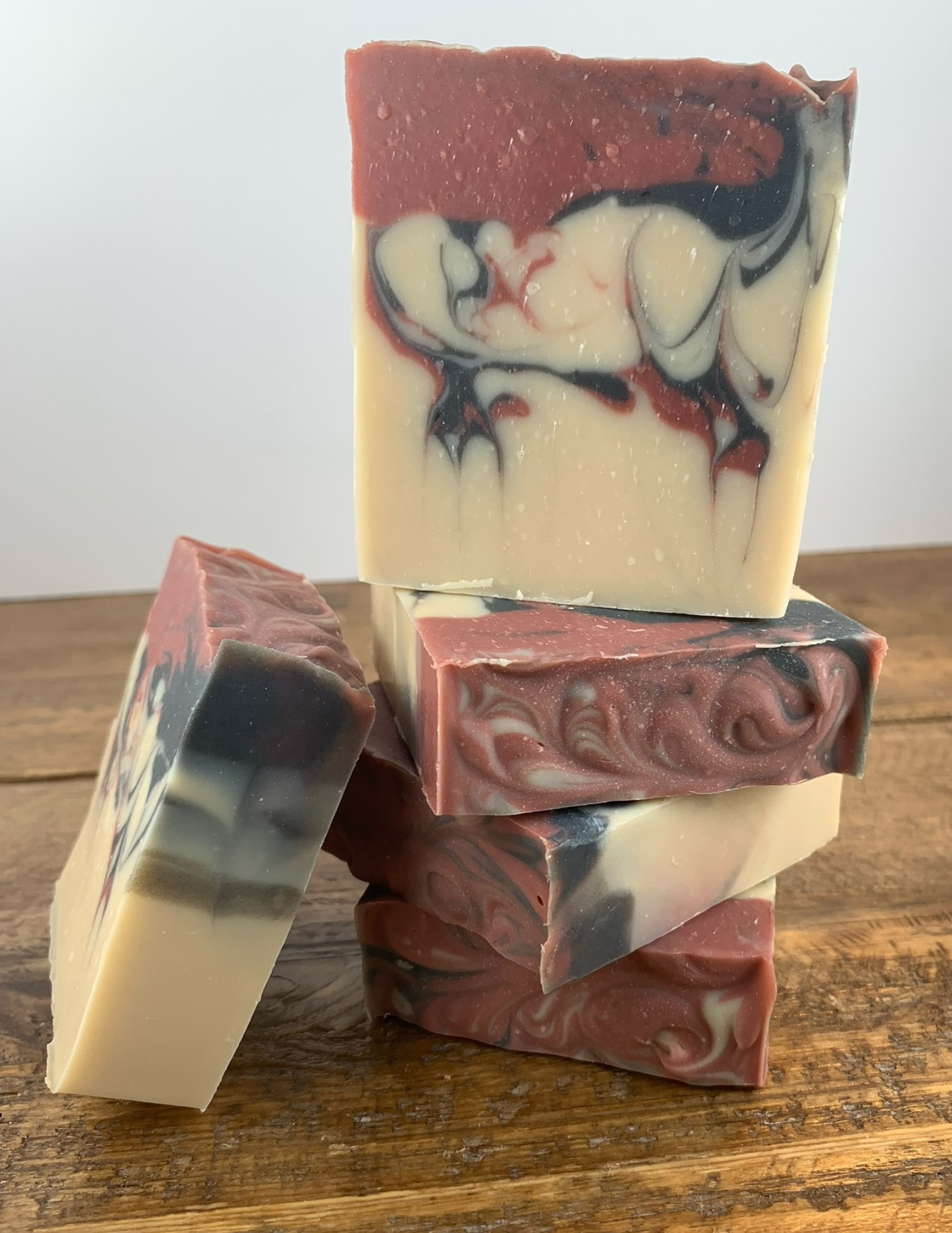 Stack of Black Raspberry Vanilla Soap on a wooden table with a white background. Another bar of soap leans against the stack