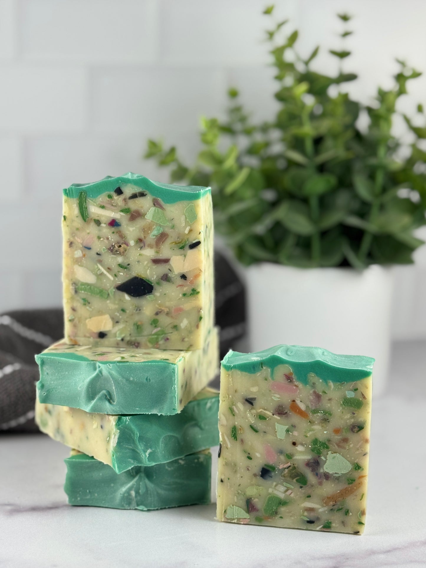 Stack of green soap bars with a plant in the background