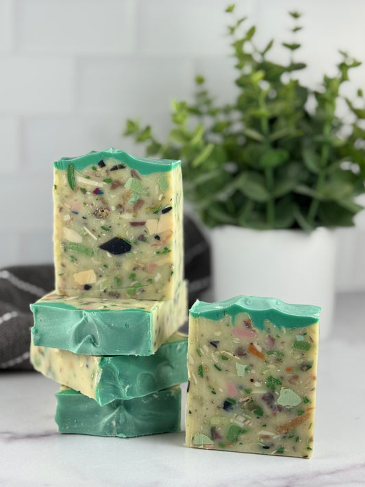 Stack of green soap bars with a plant in the background