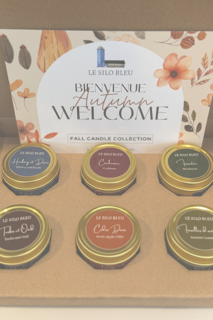 Set of six small candles in gold tins with 'Le Silo Bleu' branding, displayed in front of a 'Bienvenue Autumn Welcome' sign.
