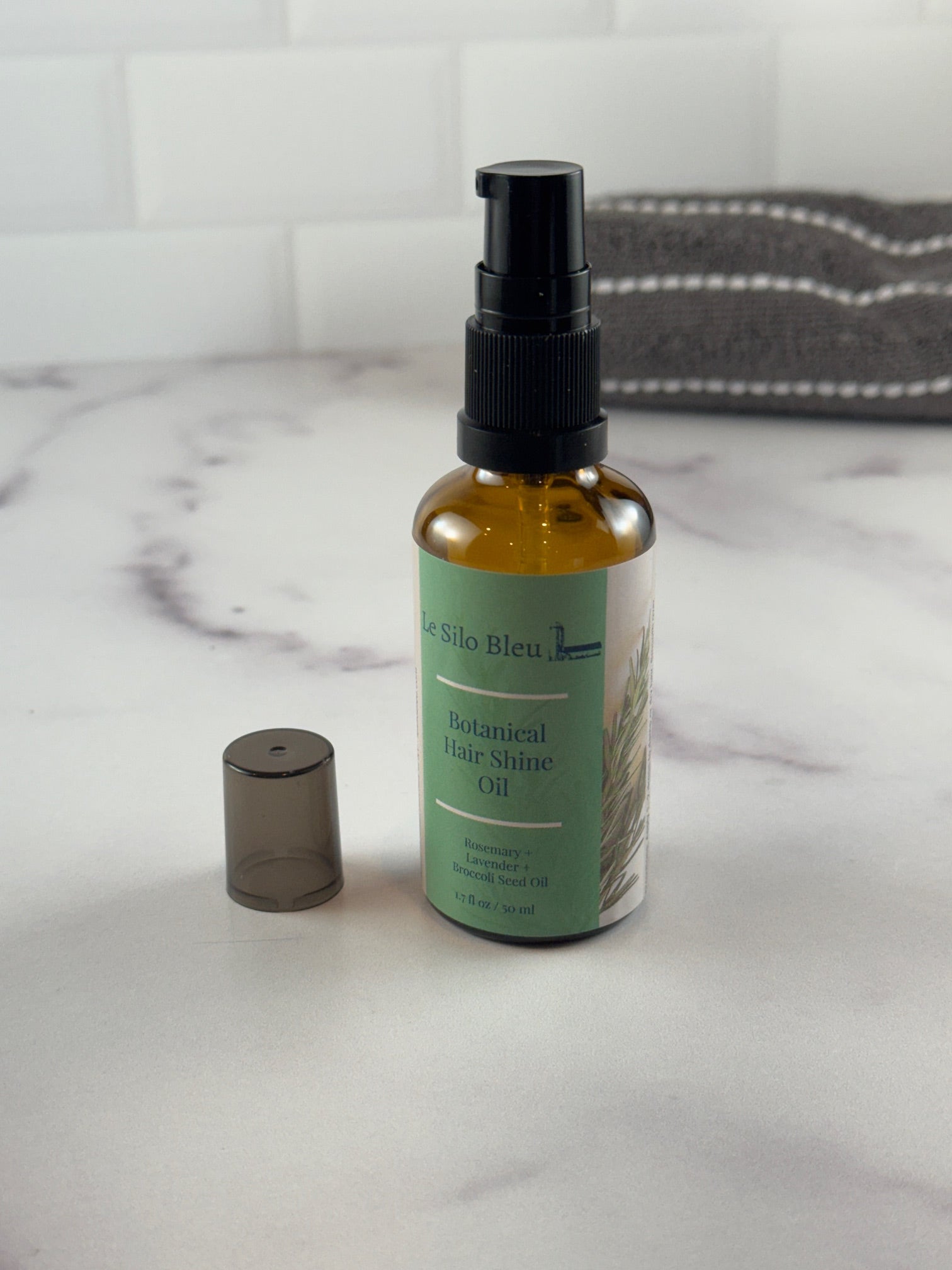 Hair oil bottle with pump on a marble surface