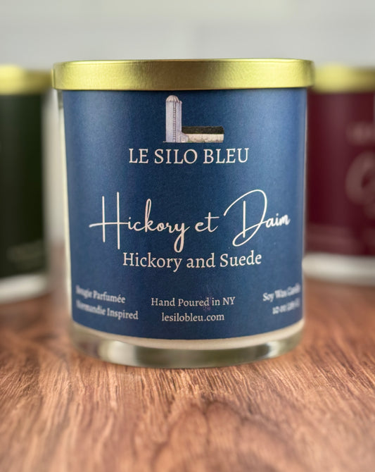Candle with 'Le Silo Bleu' Hickory & Suede label on a wooden surface