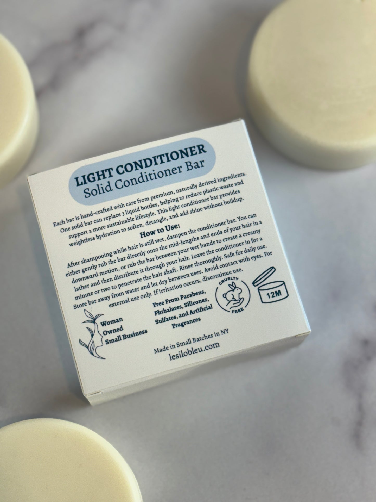 Light conditioner solid bars with  surrounding the packaging back on a marble surface