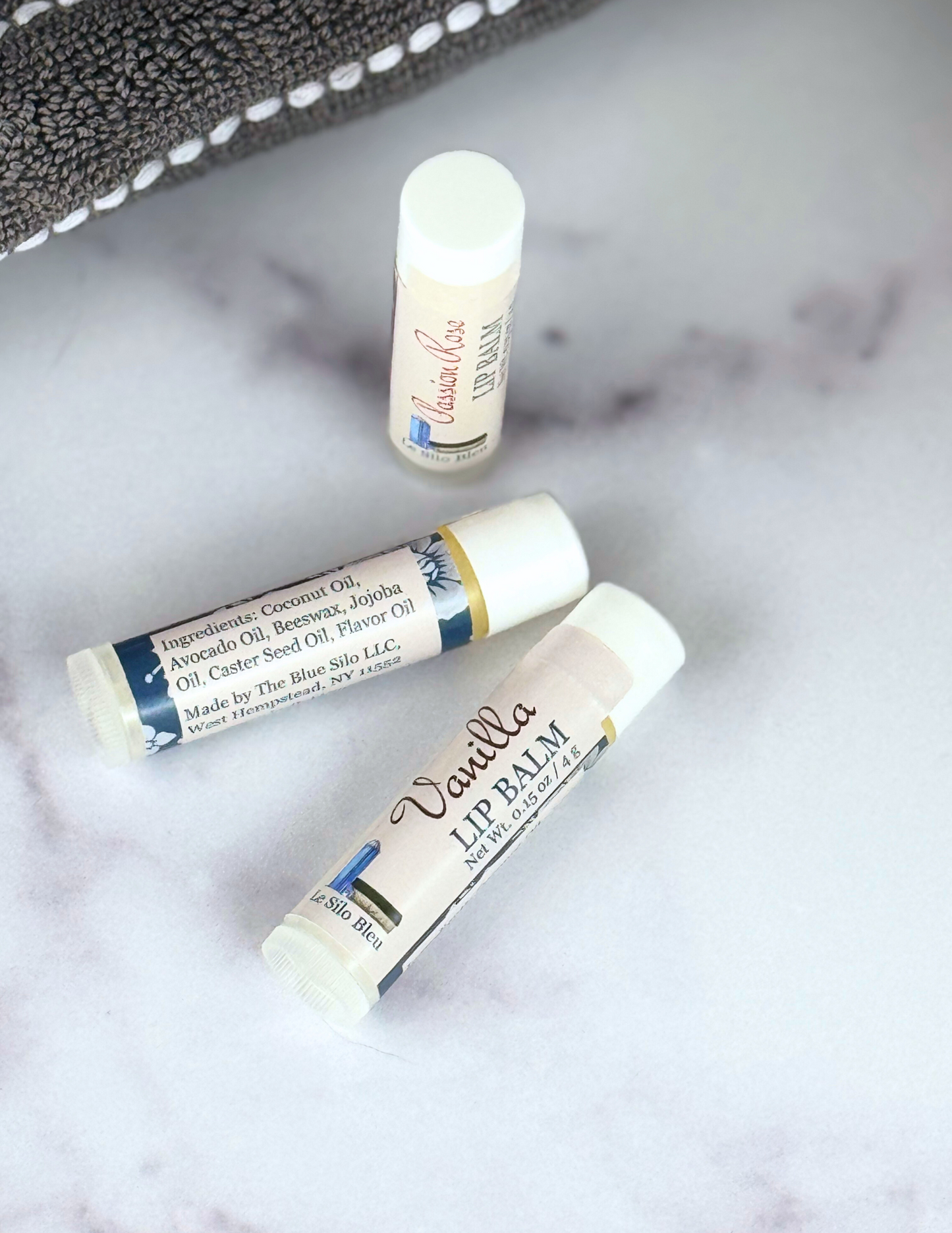 Vanilla Lip Balm and others showing ingredients on a marble table