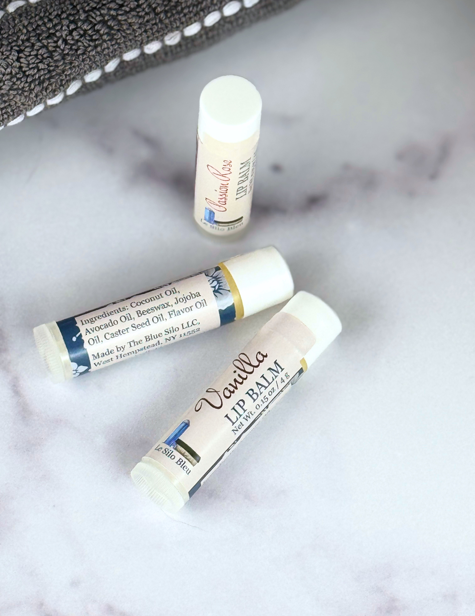 Vanilla Lip Balm and others showing ingredients on a marble table