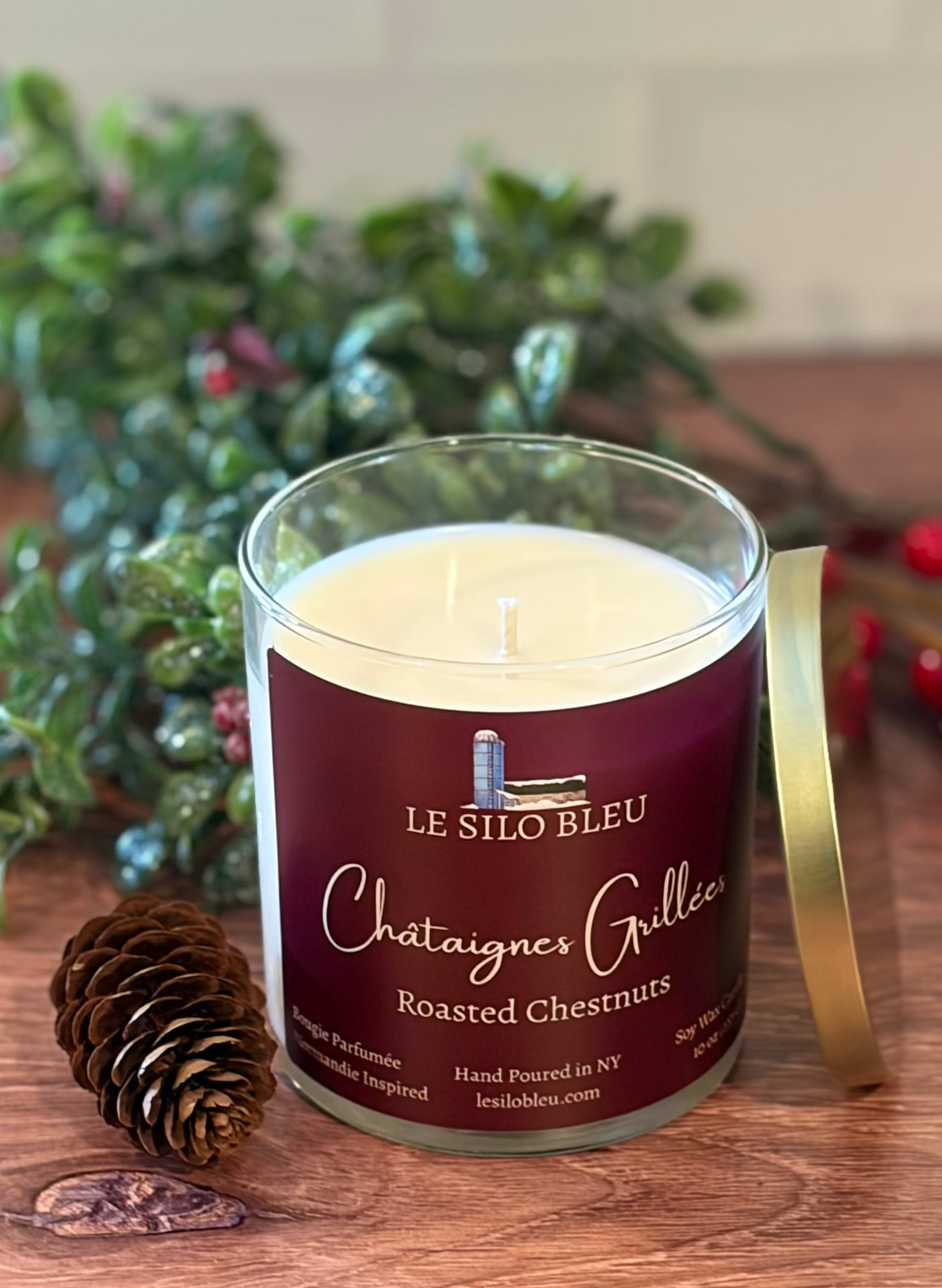 Jar of Le Silo Bleu roasted chestnuts on a wooden surface with greenry and a pineocone on the table.