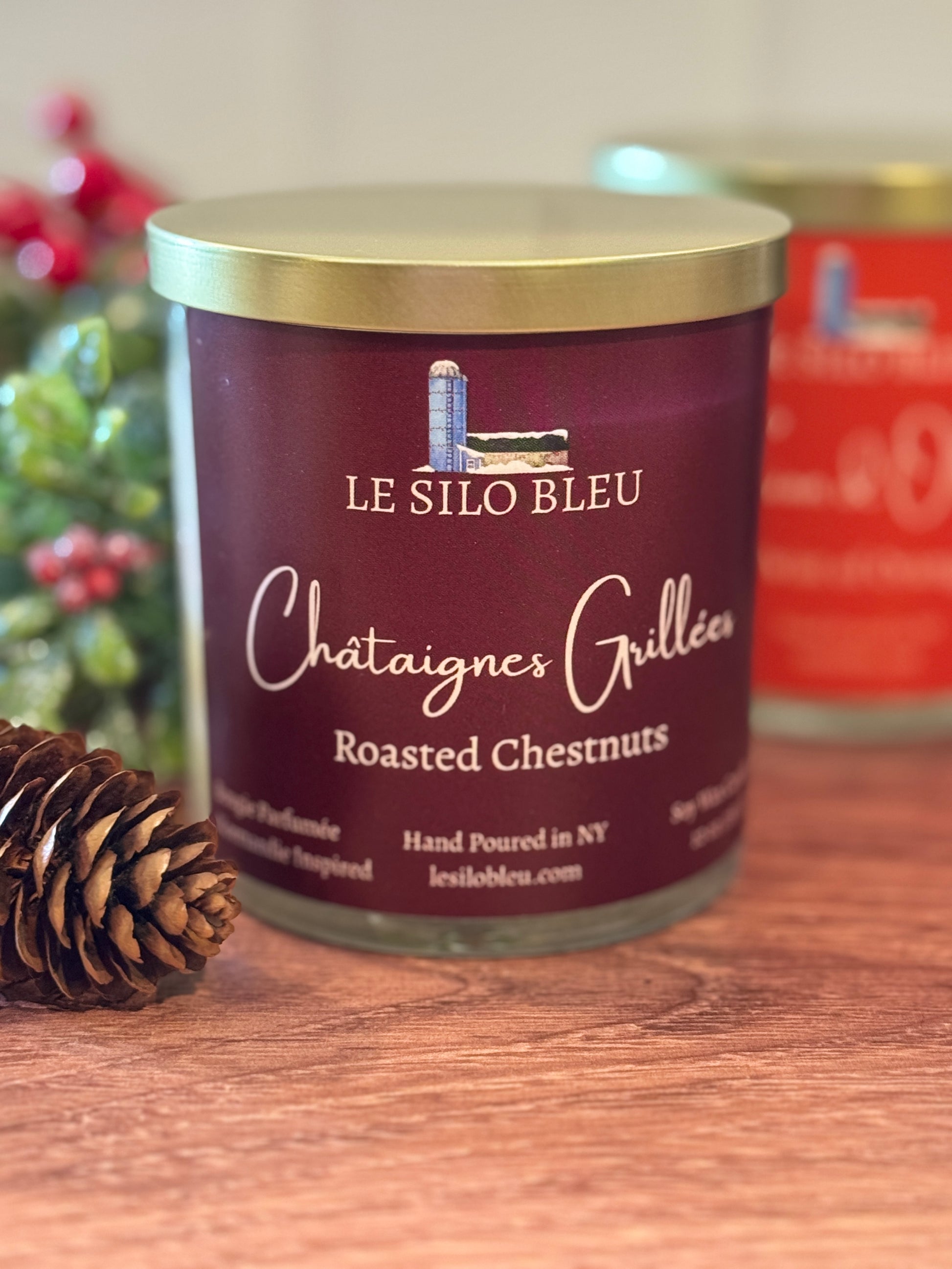 Jar of Le Silo Bleu roasted chestnuts on a wooden surface with a pine cone.