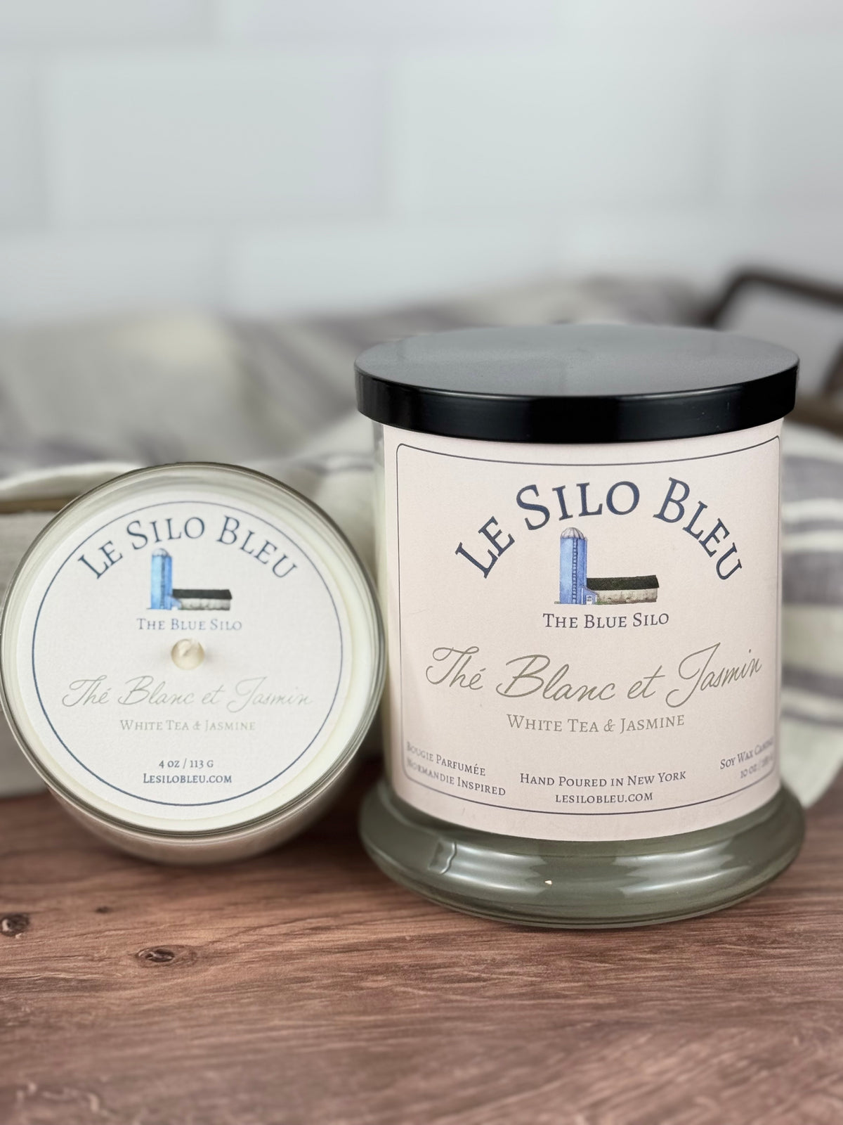 Large and small candles of white tea and jasmine on a wooden table. 