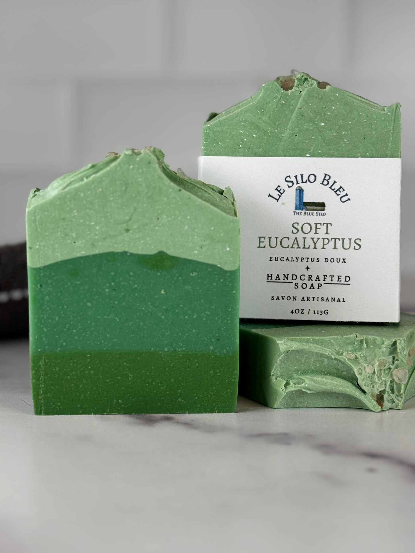 Soft eucalyptus soap with pink sea salt on top and varying layers of green color soap. On a marble table. 