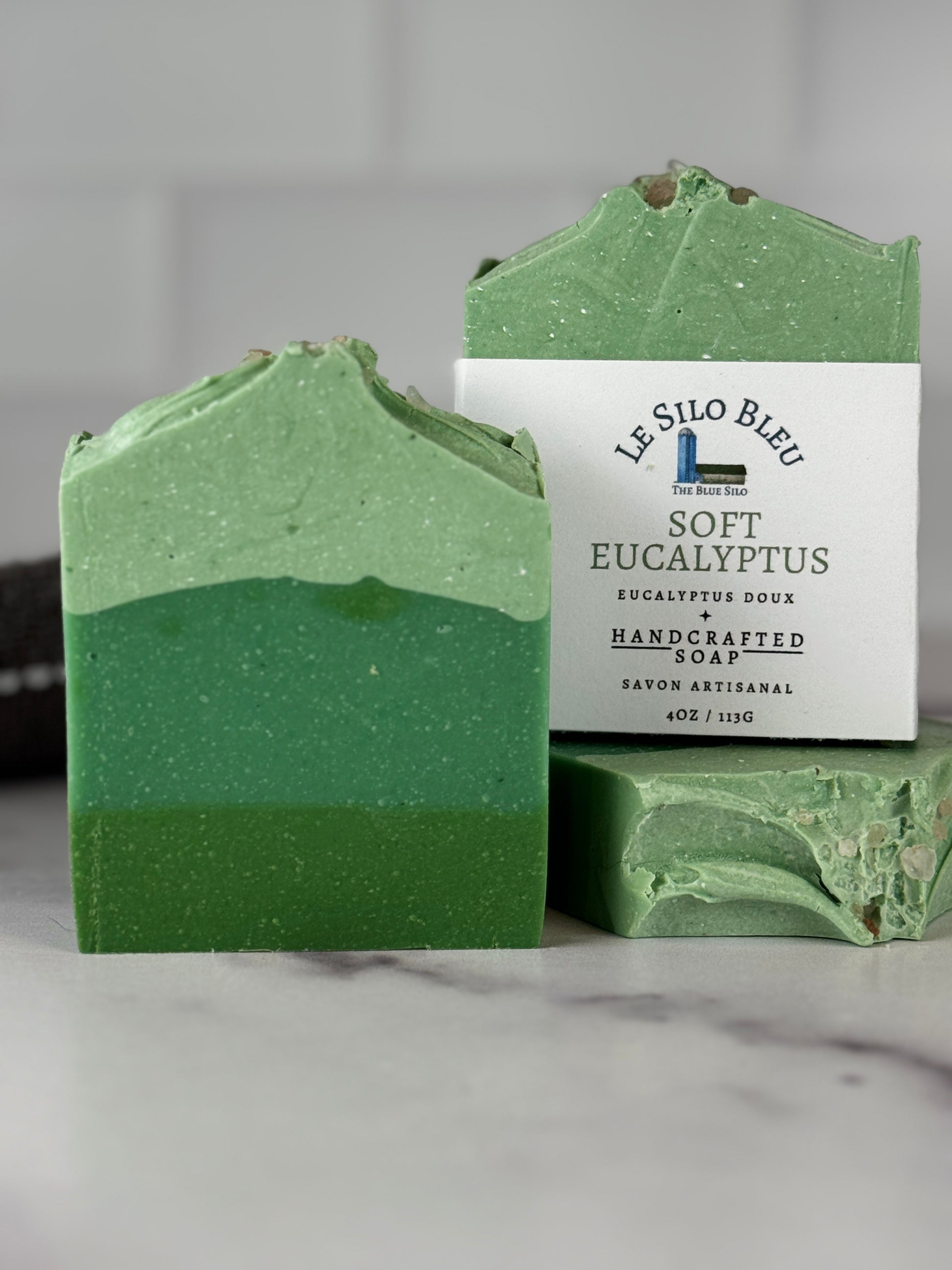 Soft eucalyptus soap with pink sea salt on top and varying layers of green color soap. On a marble table. 