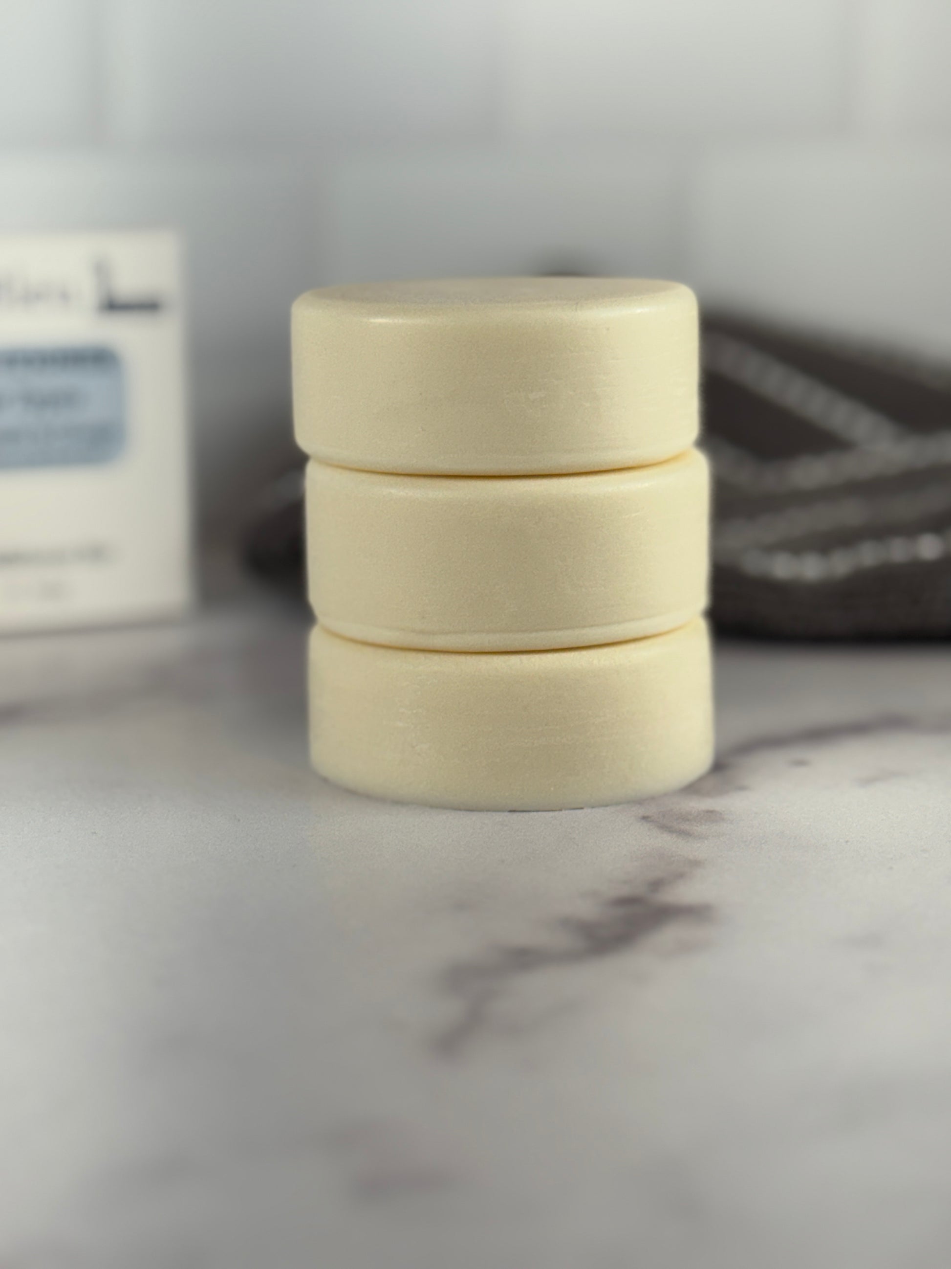 Stack of three light conditioner bars on a marble surface with a blurred background