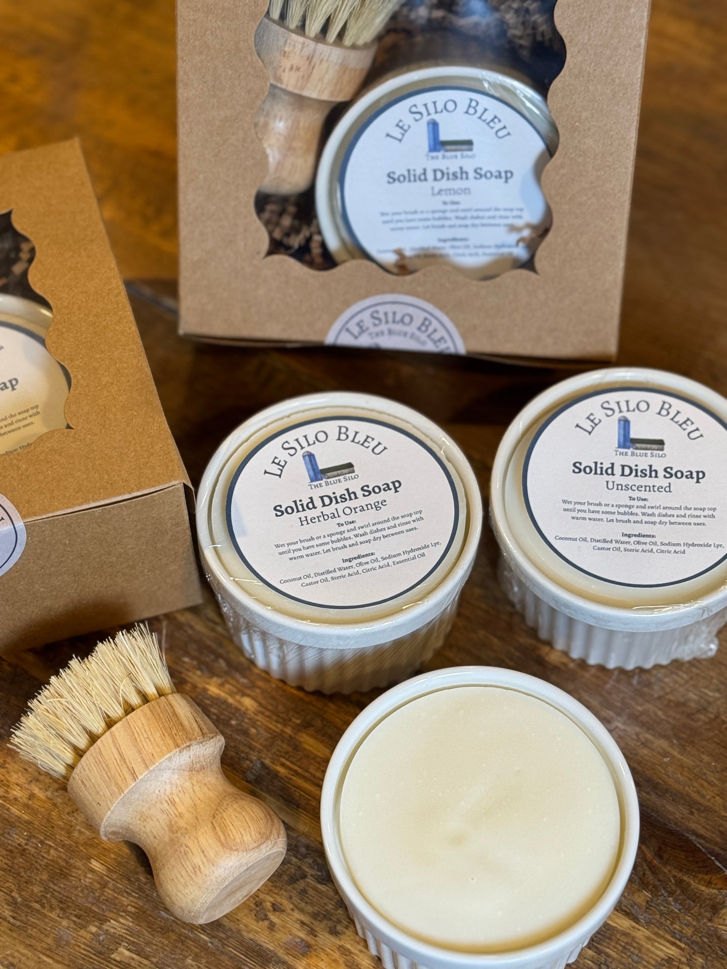 Le Silo Bleu solid dish soap sets of white ramekins with a wooden dish brush on a wooden tabletop