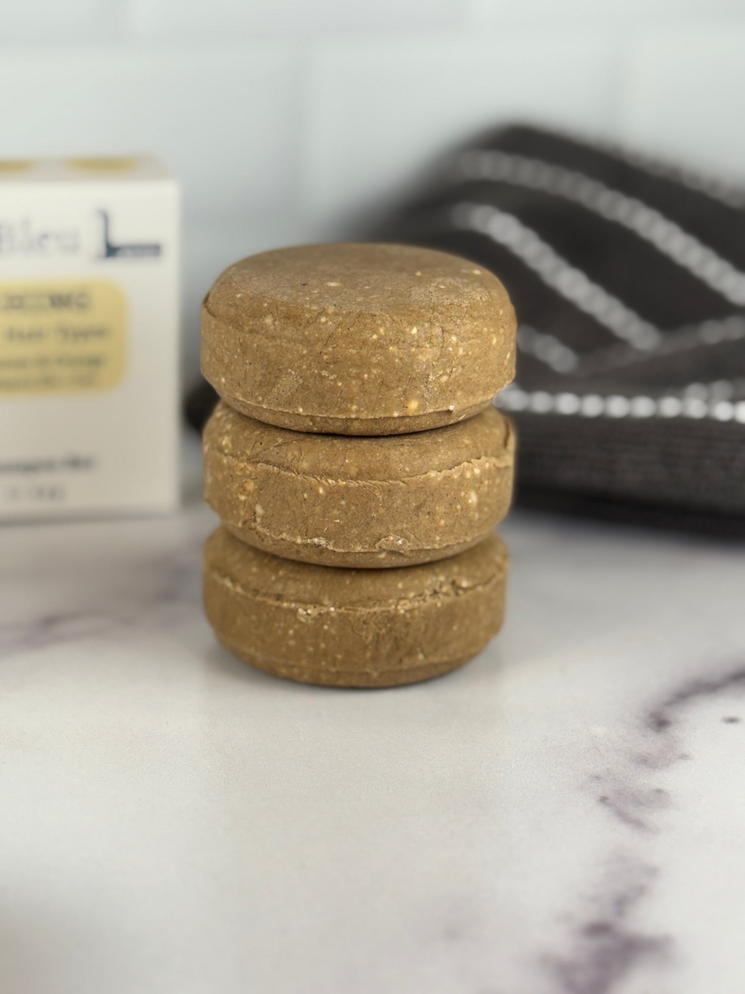 Stack of Nourishing Solid Shampoo bars on a marble surface with a blurred background