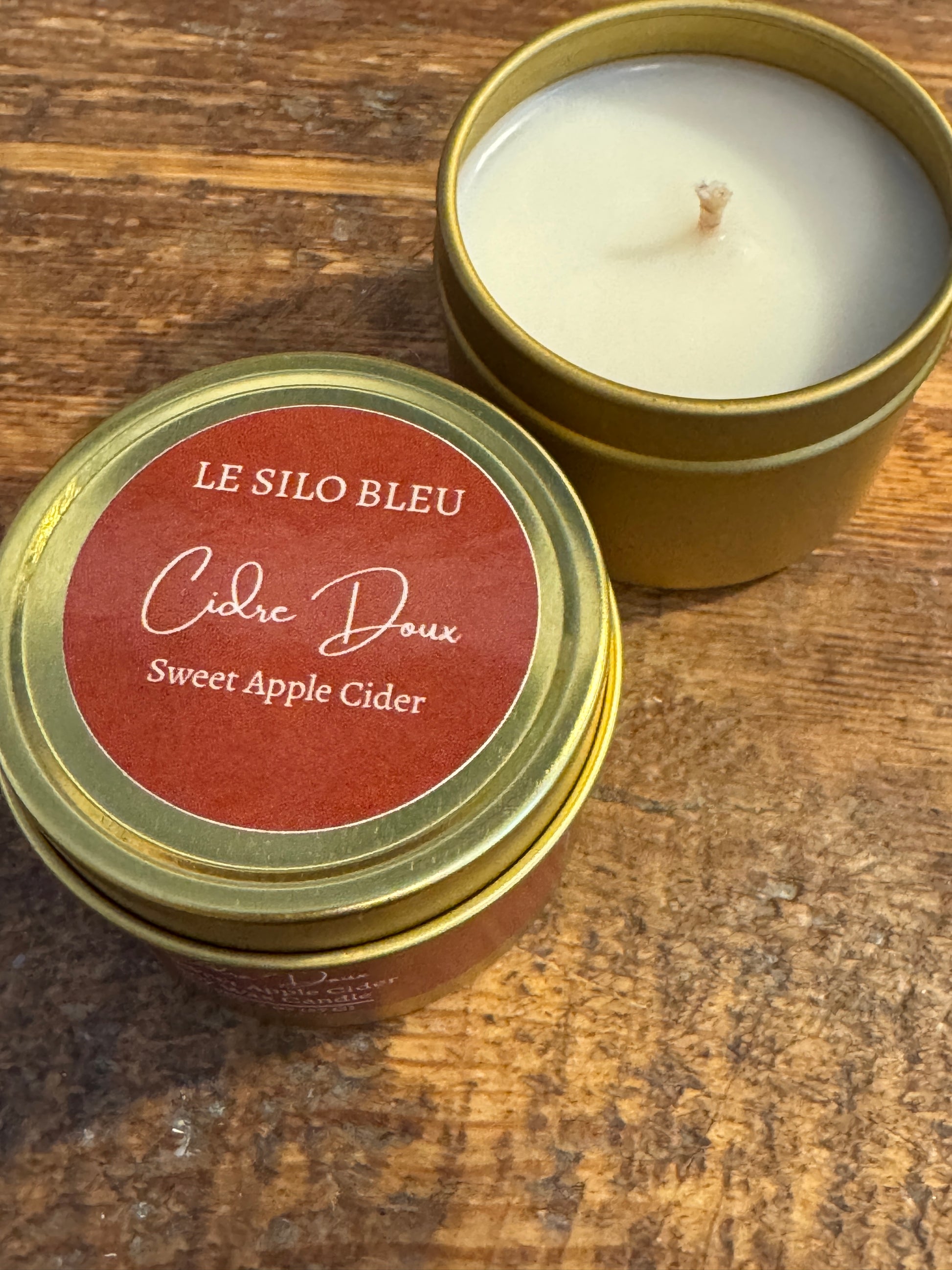 Candle in a tin with a red label on a wooden surface